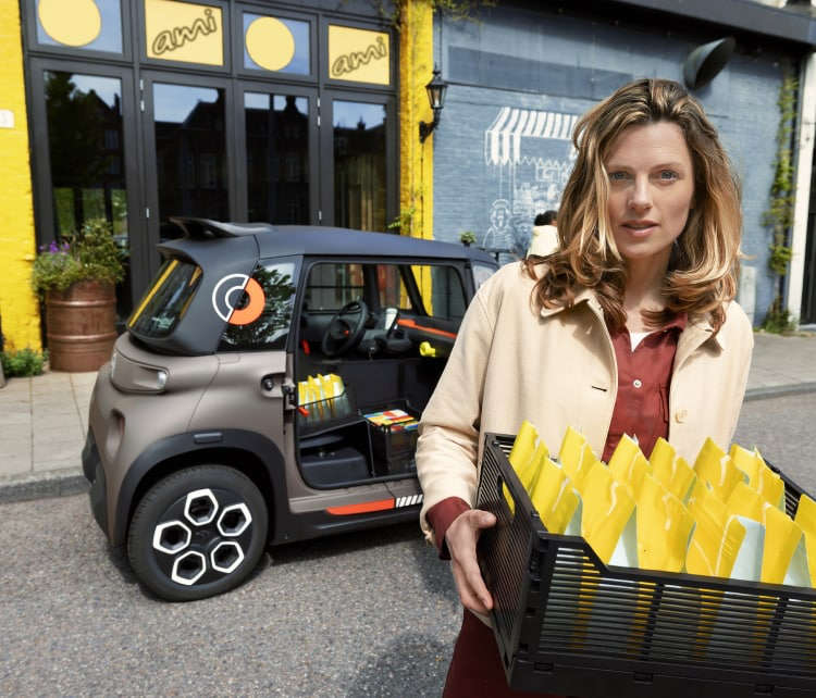Дівчине забирає коробку з речами з CITROЁN Ami