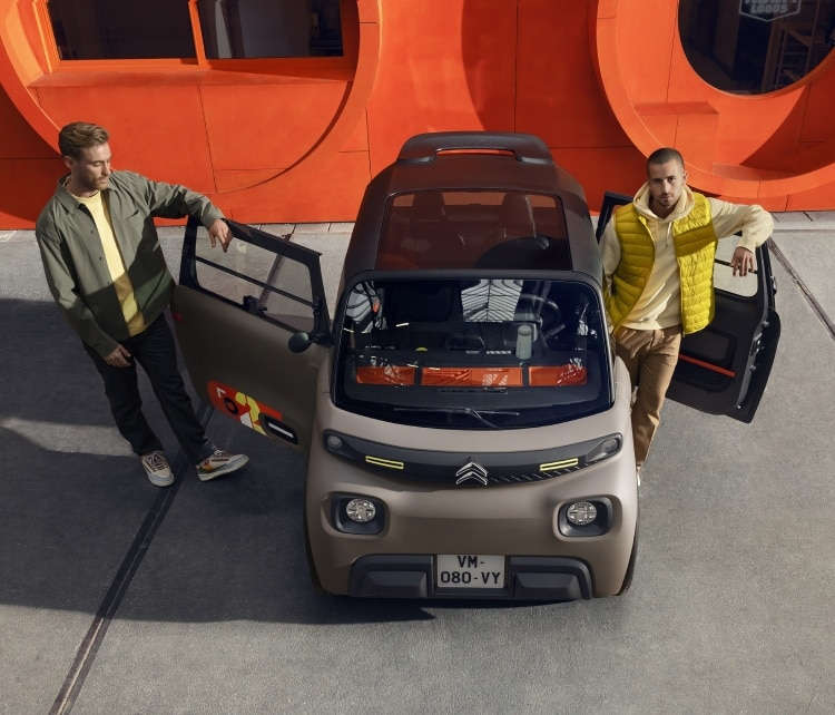Двоє чоловіків стоять біля відчинених дверей Citroën Ami на вулиці